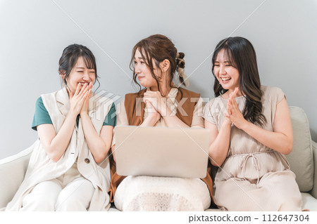 Women, friends, mom friends, and colleagues using laptops at home with friends 112647304