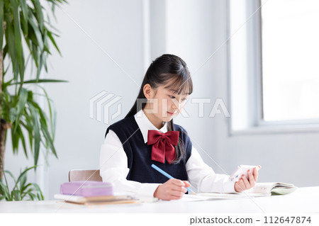 Junior high school girl studying while looking at her smartphone 112647874