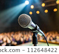 一支麥克風站在燈光照亮的舞台上 112648422
