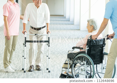 Elderly people in wheelchairs and young helpers who care Elderly people in wheelchairs and young helpers who care 112648696