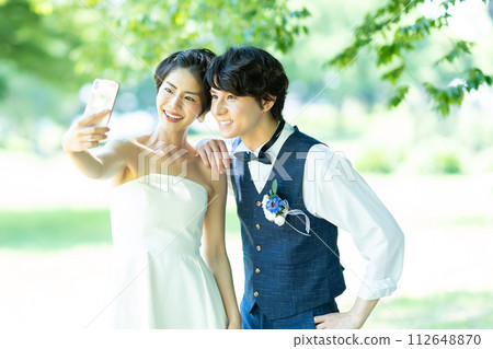 Bride and groom taking photos with smartphone Bride and groom taking photos with smartphone 112648870