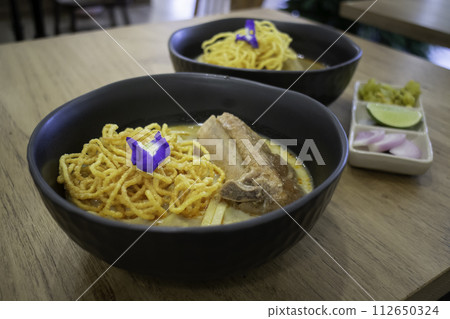 Thai noodles Khao Soi, spicy curry with seasoning on table Thai noodles Khao Soi, spicy curry with seasoning on table 112650324