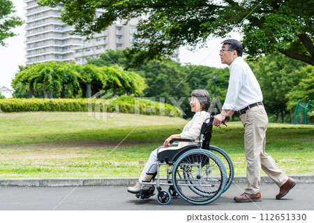 Senior couple walking in a wheelchair 112651330