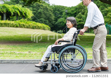 Senior couple walking in a wheelchair 112651331