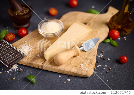 Piece of Traditional Italian Parmesan Hard cheese on a wooden cutting board at domestic kitchen Piece of Traditional Italian Parmesan Hard cheese on a wooden cutting board at domestic kitchen 112651745