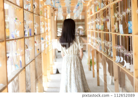 A woman looking at wind chimes at a shrine A woman looking at wind chimes at a shrine 112652089