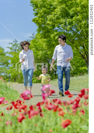 A family of three walking through a park filled with poppies A family of three walking through a park filled with poppies 112652401