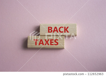 Back Taxes symbol. Concept word Back Taxes on wooden blocks. Beautiful pink background. Business and Back Taxes concept. Copy space 112652963