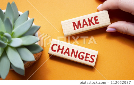 Make changes symbol. Wooden blocks with words Make changes with succulent plant. Beautiful orange background. Businessman hand. Business and Make changes concept. Copy space. 112652987