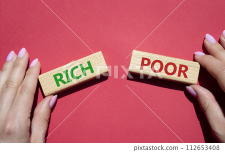 Rich vs Poor symbol. Concept word Rich vs Poor on wooden blocks. Businessman hand. Beautiful red background. Business and Rich vs Poor concept. Copy space 112653408