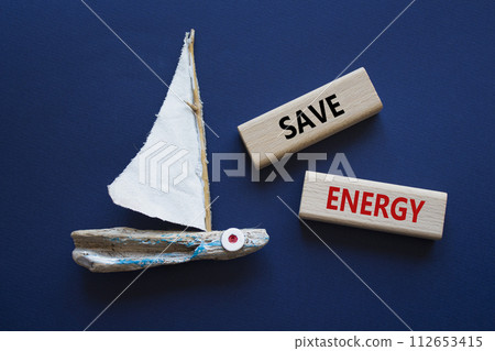 Save Energy symbol. Wooden blocks with words Save Energy. Beautiful deep blue background with boat. Business and Save Energy concept. Copy space. Save Energy symbol. Wooden blocks with words Save Energy. Beautiful deep blue background with boat. Business and Save Energy concept. Copy space. 112653415