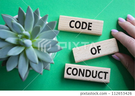 Code of conduct symbol. Wooden blocks with words Code of conduct. Beautiful green background with succulent plant. Businessman hand. Business and Code of conduct concept. Copy space. Code of conduct symbol. Wooden blocks with words Code of conduct. Beautiful green background with succulent plant. Businessman hand. Business and Code of conduct concept. Copy space. 112653426