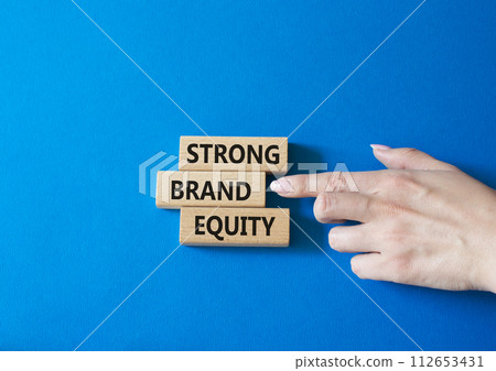 Strong Brand Equity symbol. Concept words Strong Brand Equity on wooden blocks. Businessman hand. Beautiful blue background. Business and Strong Brand Equity concept. Copy space 112653431