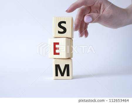 SEM - Search Engine Marketing symbol. Wooden cubes with words SEM. Businessman hand. Beautiful white background. Business and SEM concept. Copy space. 112653464