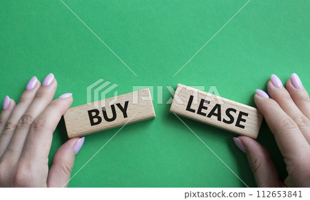 Buy or Lease symbol. Concept word Buy or Lease on wooden blocks. Businessman hand. Beautiful green background. Business and Buy or Lease concept. Copy space 112653841
