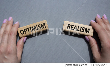 Optimism or Realism symbol. Concept word Optimism or Realism on wooden blocks. Businessman hand. Beautiful grey background. Business and Optimism or Realism concept. Copy space 112653846