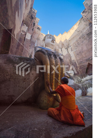 A monk with the buddha finger in Wat Si Chum in Sukhothai Historical Park, pagoda stupa, Sukhothai, Thailand. Thai buddhist temple architecture. Tourist attraction. People lifestyle. 112653988