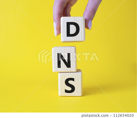 DNS -Domain Name Server - Consumer Price Index symbol. Concept word DNS on wooden cubes. Businessman hand. Beautiful yellow background. Business and DNS concept. Copy space. 112654020