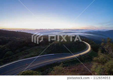 Aerial view of national park Inthanon, cars driving on curved, zigzag curve road or street on mountain hill with green natural forest trees in rural area of Chiang Mai, Thailand. Aerial view of national park Inthanon, cars driving on curved, zigzag curve road or street on mountain hill with green natural forest trees in rural area of Chiang Mai, Thailand. 112654053