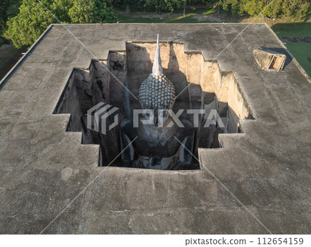 Aerial view of The buddha in Wat Si Chum in Sukhothai Historical Park, pagoda stupa, Sukhothai, Thailand. Thai buddhist temple architecture. Tourist attraction. Aerial view of The buddha in Wat Si Chum in Sukhothai Historical Park, pagoda stupa, Sukhothai, Thailand. Thai buddhist temple architecture. Tourist attraction. 112654159