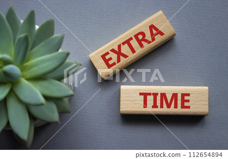 Extra time symbol. Concept word Extra time on wooden blocks. Beautiful grey background with succulent plant. Business and Extra time concept. Copy space Extra time symbol. Concept word Extra time on wooden blocks. Beautiful grey background with succulent plant. Business and Extra time concept. Copy space 112654894