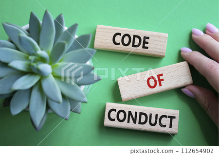 Code of conduct symbol. Wooden blocks with words Code of conduct. Beautiful green background with succulent plant. Businessman hand. Business and Code of conduct concept. Copy space. 112654902