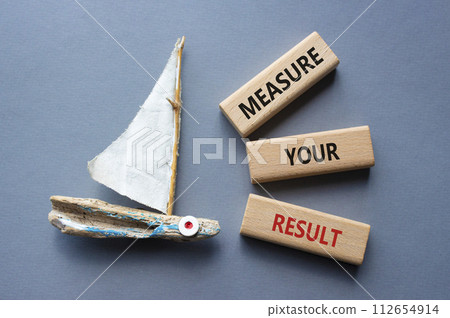 Measure your Result symbol. Concept words Measure your Result on wooden blocks. Beautiful grey background with boat. Business and Measure your Result concept. Copy space. 112654914