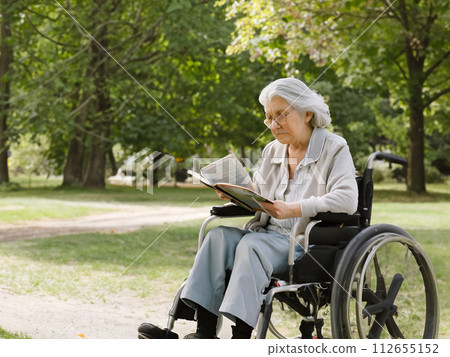 Senior woman reading in a wheelchair 112655152