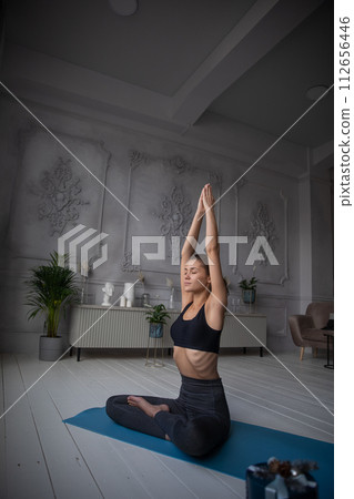 young woman sits at the yoga pose at home young woman sits at the yoga pose at home 112656446