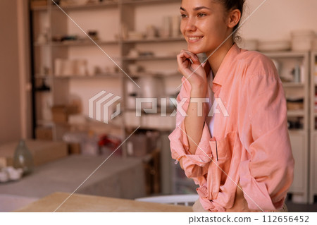 Hands of a woman, sitting at the wooden table clay workshop Hands of a woman, sitting at the wooden table clay workshop 112656452