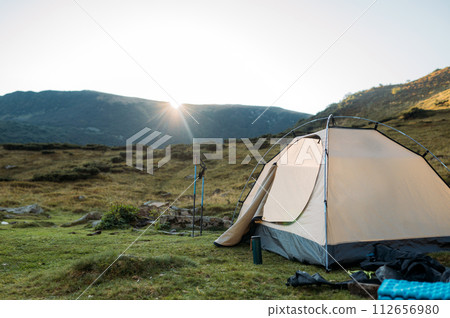 tent set in the mountains at sunset. The concept of active recreation tent set in the mountains at sunset. The concept of active recreation 112656980