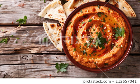 Roasted red pepper hummus with pita bread on wooden background. Roasted red pepper hummus with pita bread on wooden background. 112657041