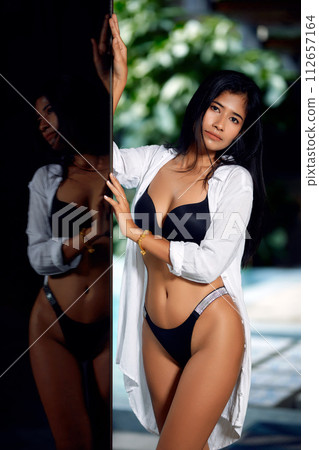 Young asian sexy girl in a white bikini posing at hotel territory Young asian sexy girl in a white bikini posing at hotel territory 112657164