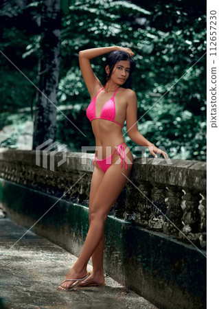 Young beautiful asian woman posing at tropical park Young beautiful asian woman posing at tropical park 112657230