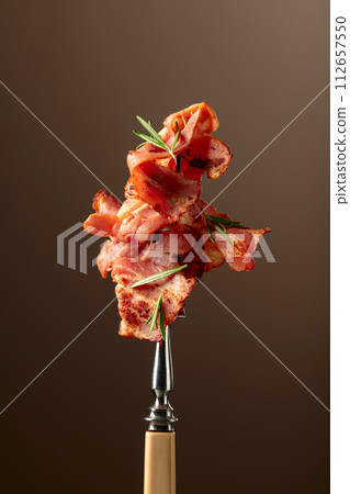 Roasted bacon with rosemary on a fork. Roasted bacon with rosemary on a fork. 112657550