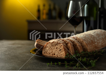 Freshly cut bread with red wine on a kitchen table. Freshly cut bread with red wine on a kitchen table. 112657554