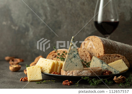 Cheese, bread, red wine, and walnuts on a stone table. Cheese, bread, red wine, and walnuts on a stone table. 112657557