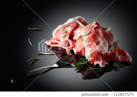 Italian prosciutto or Spanish jamon with rosemary. Italian prosciutto or Spanish jamon with rosemary. 112657575