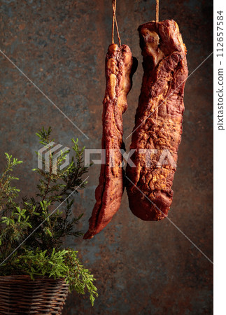 Homemade smoked pork ribs with juniper branches on a rusty background. 112657584