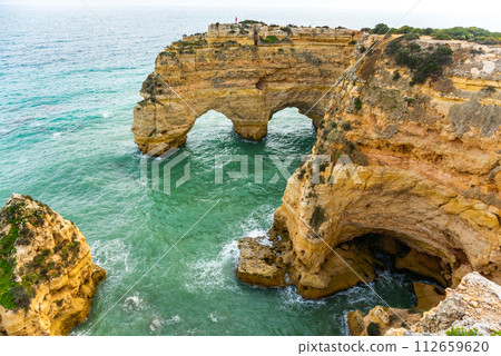 Natural caves and beach, Algarve Portugal. Rock cliff arches of Seven Hanging Valleys and turquoise sea water on coast of Portugal in Algarve region 112659620