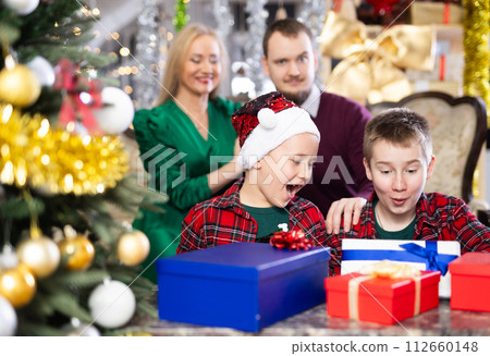 Children and parents give each other gift boxes during Christmas or New Year celebrations at home Children and parents give each other gift boxes during Christmas or New Year celebrations at home 112660148