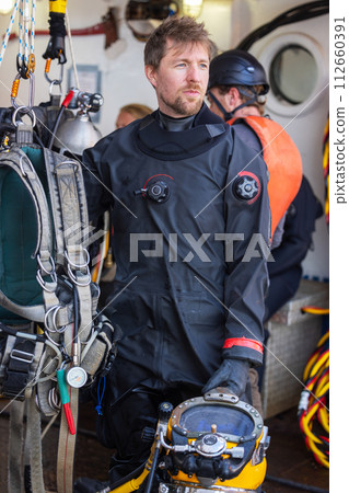 Commercial Diver holding helmet in industrial harbour 112660391