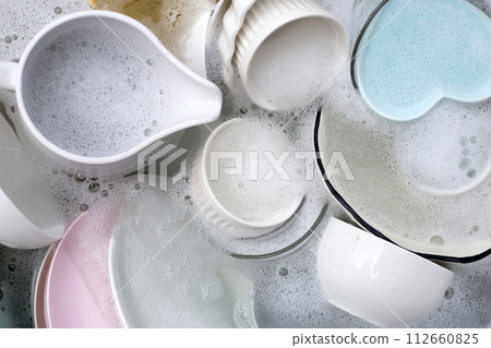 Dishes and bowls in water and bubbles of dishwashing liquid. Kitchen work 112660825
