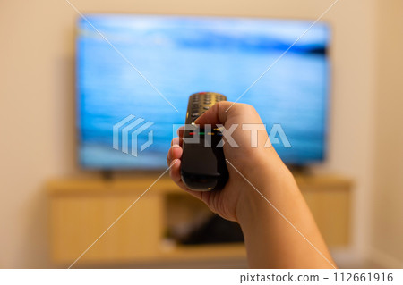 Hand holding TV remote control Hand holding TV remote control 112661916