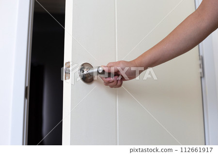 The man's hand is opening the door of the room. 112661917