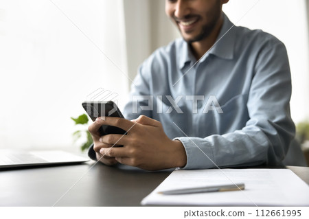 Close up of young Indian man chatting on mobile phone 112661995