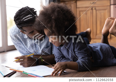 African dad and daughter drawing pictures in paper with pencils African dad and daughter drawing pictures in paper with pencils 112662038