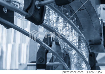 The  empty drinking water bottles  hanging on the conveyor belt for filling process. 112662457