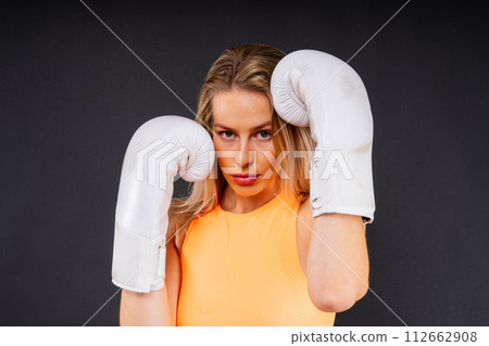 Female boxer hitting at a boxing studio. Woman in gloves training hard. 112662908