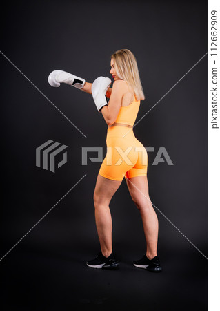 Female boxer hitting at a boxing studio. Woman in gloves training hard. 112662909